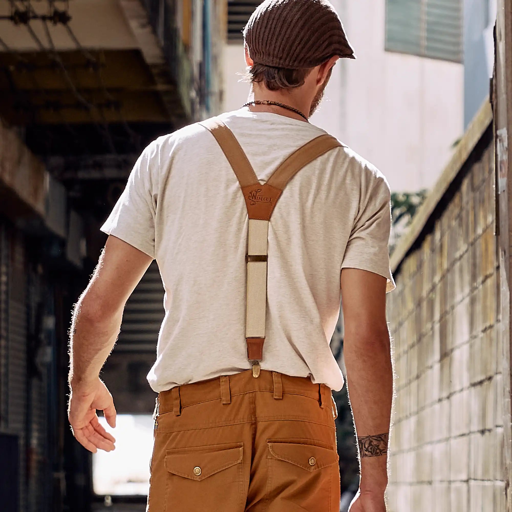 Man walking through streets wearing a flat cap and Wiseguy Original Suspenders.