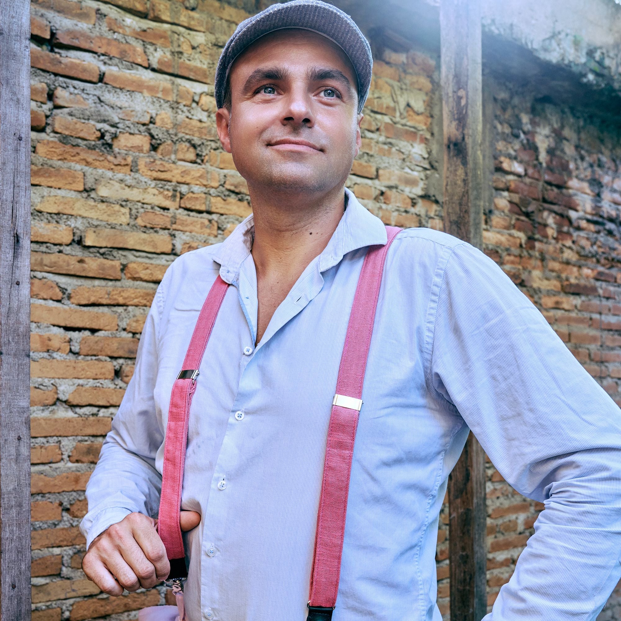 Man wearing a subtly striped shirt, flatcap and pink Suspenders.